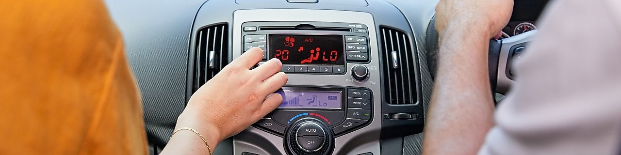 A car passenger adjusts their conditioning dial, while the driver's side air conditioning is set to low.