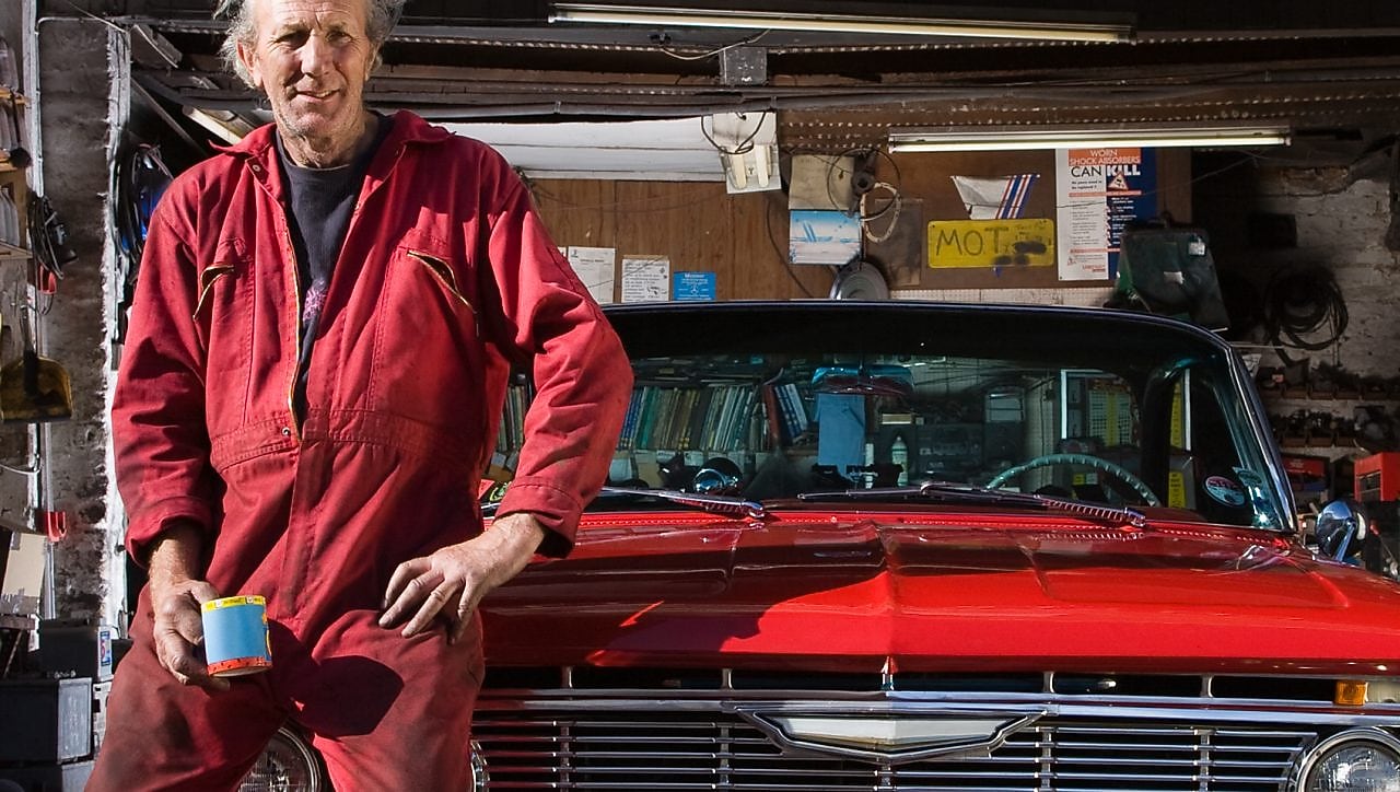 Man sitting on red cars bonnet