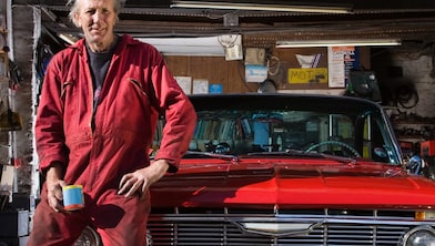 Man sitting on red cars bonnet