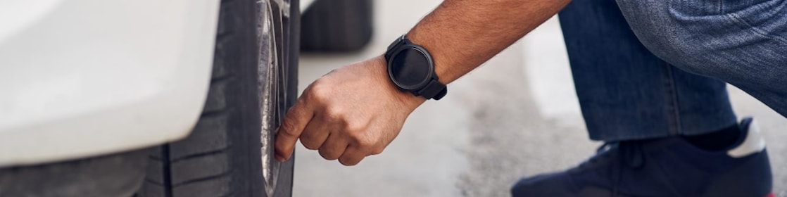 Person checking their tyres of non-moving car