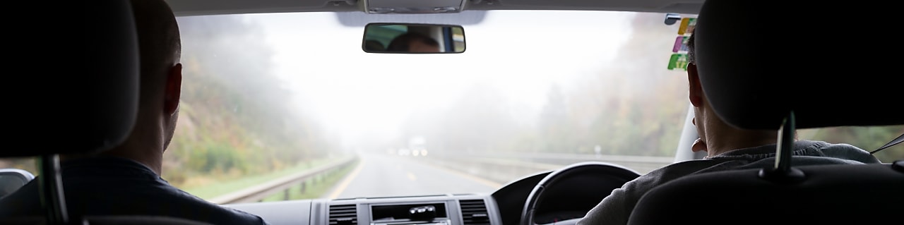 Two people in car driving through fog