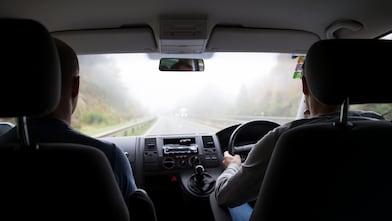 Two people in car driving through fog