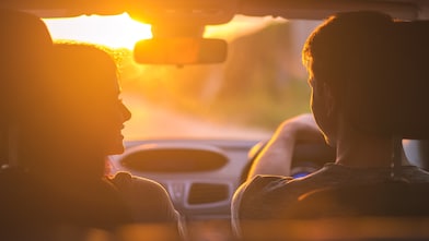 The couple drive a car on the background of the sunset