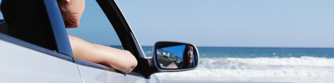 woman in non-moving car looking out to the sea