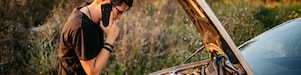 Man looking under the bonnet and on the phone