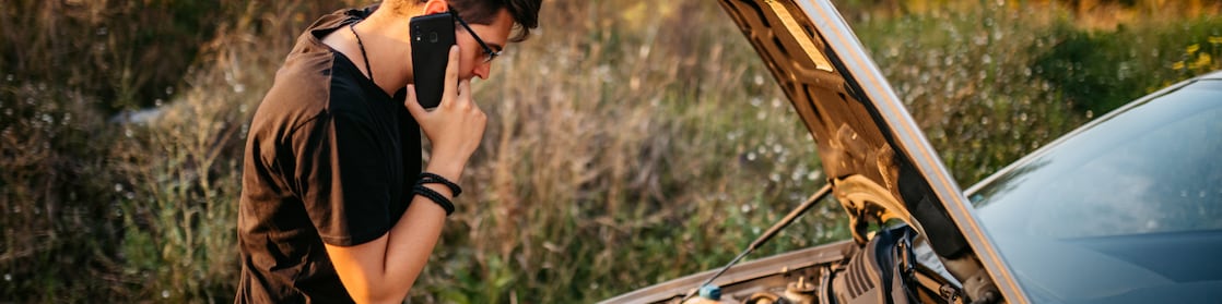 Man looking under the bonnet and on the phone