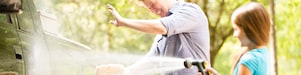father and daughter cleaning the car, daughter hosing the car
