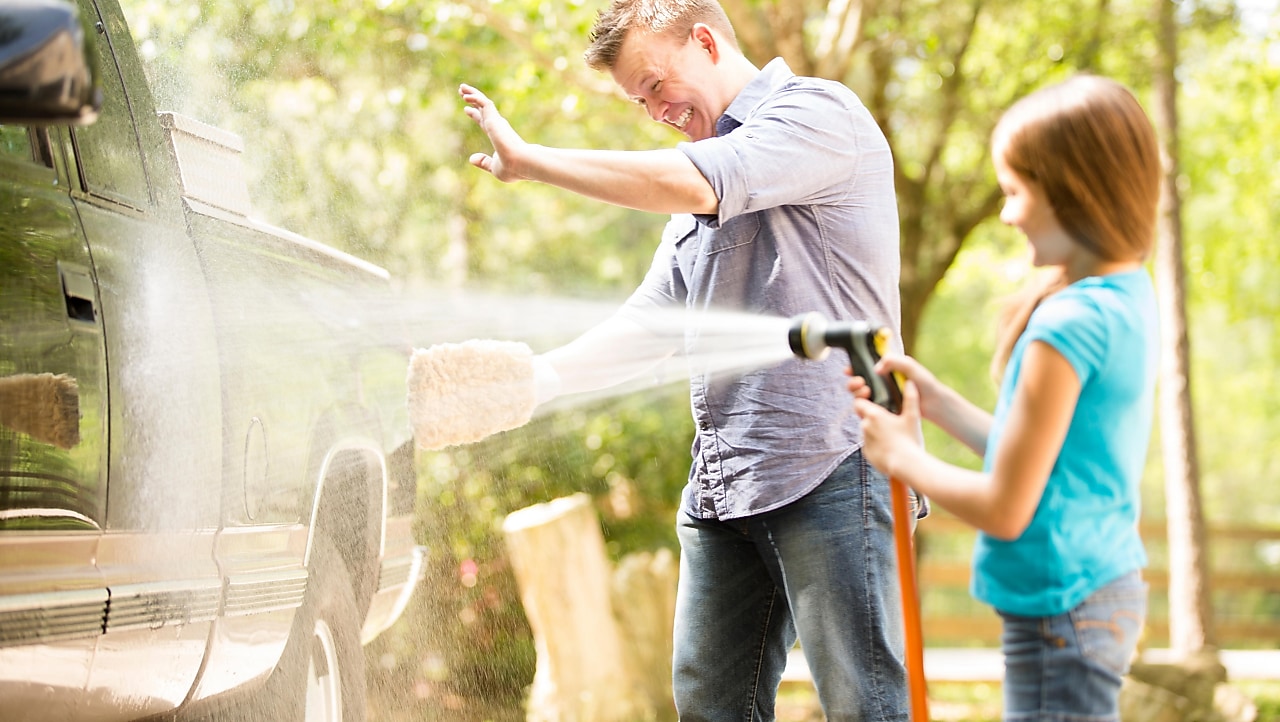 father and daughter cleaning the car, daughter hosing the car