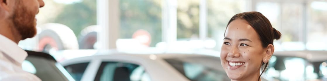 A woman is handed a key at a car dealership