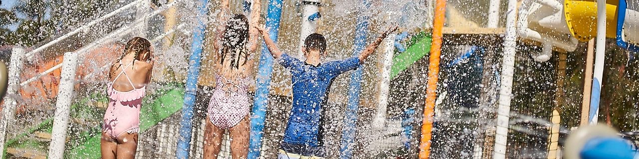 Three kids standing under water at a holiday park