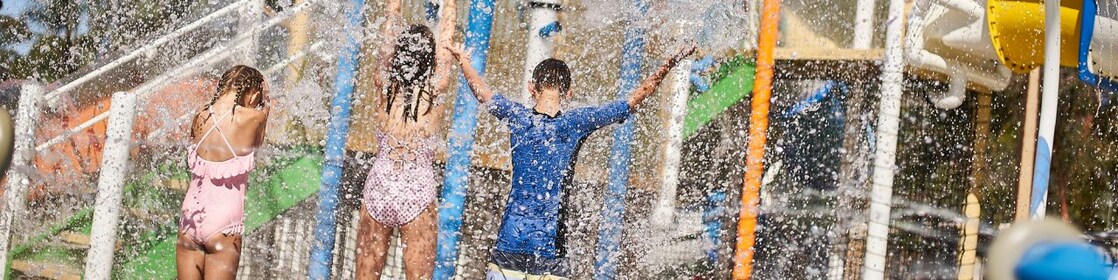 Three kids standing under water at a holiday park
