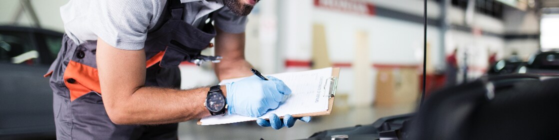 Man looking under the bonnet of car and doing safety check