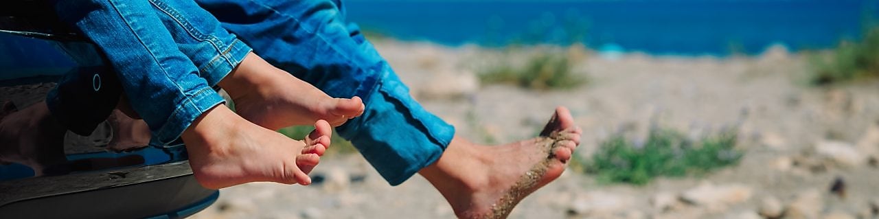 Children in a car with sand on their feet