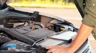 A man inspecting the engine of a car, focused on ensuring its proper functioning and maintenance.
