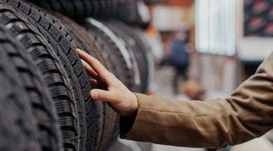 A man examines a tire while standing in a store, showcasing his interest in purchasing a new tire.