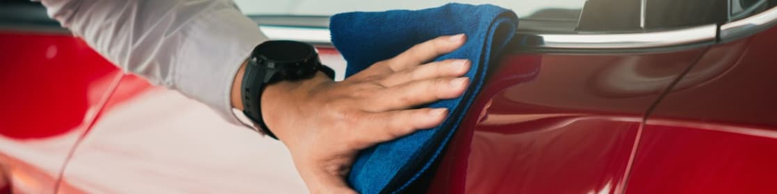 A man wipes down a red car door