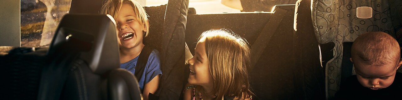 two kids and one baby sitting in the back of the car