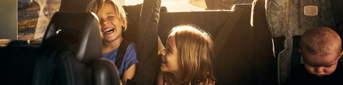 two kids and one baby sitting in the back of the car