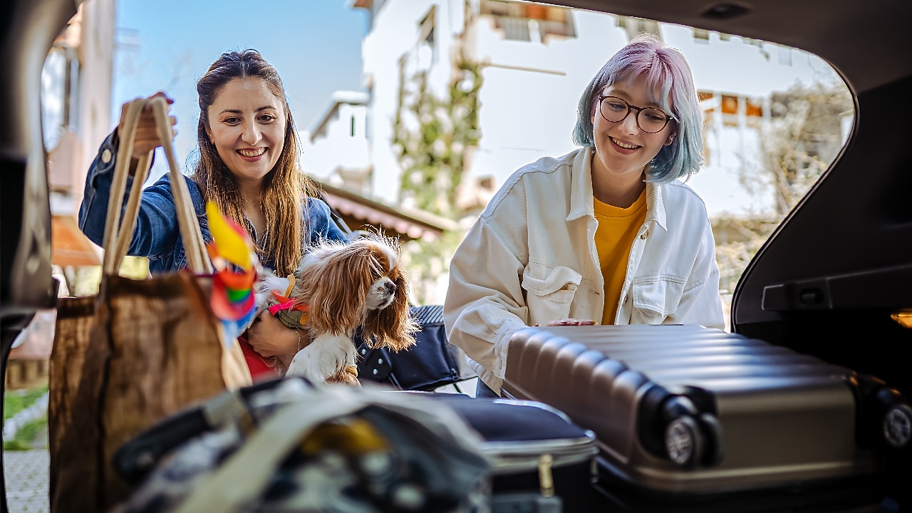 Safe and scree-free road trips: Mother and daughter packing bags at the boot of car