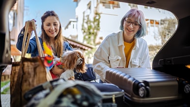 Safe and scree-free road trips: Mother and daughter packing bags at the boot of car