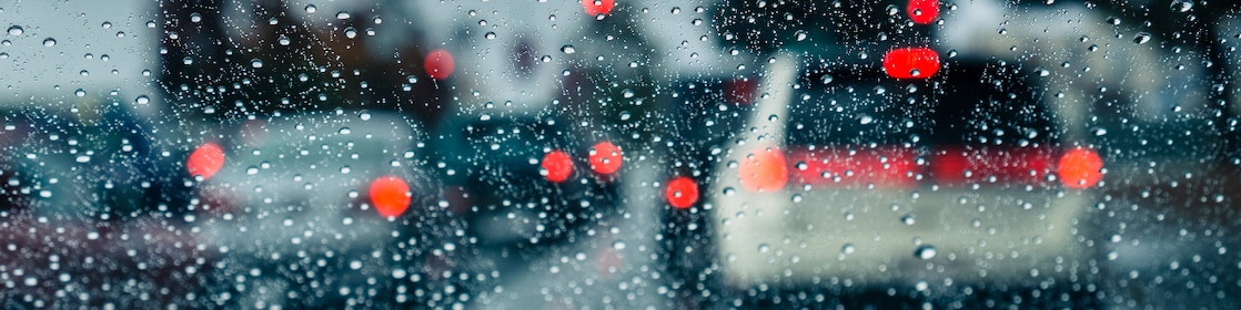 How to drive safely in a storm: Rain on car window looking out to ongoing traffic