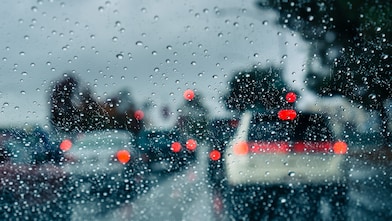 How to drive safely in a storm: Rain on car window looking out to ongoing traffic