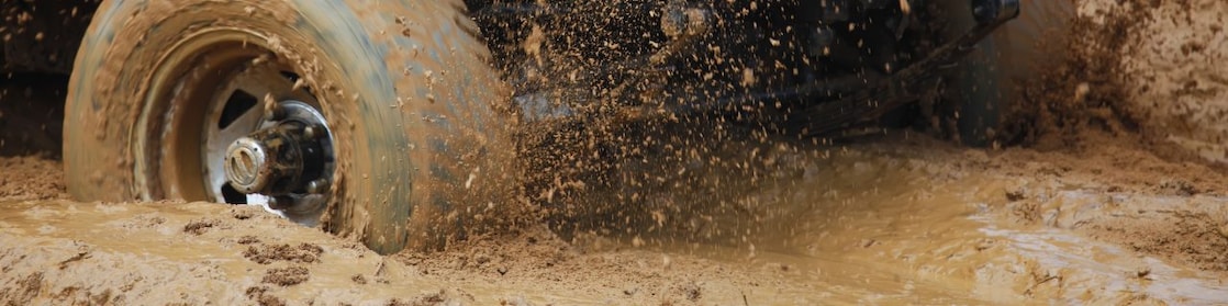 A yellow utility vehicle with its wheels bogged in mud.