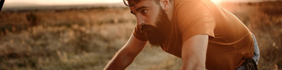A man inspects his engine by the side of the road at sunset.