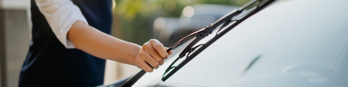 Image of an Asian woman checking her windshield wipers before her journey.