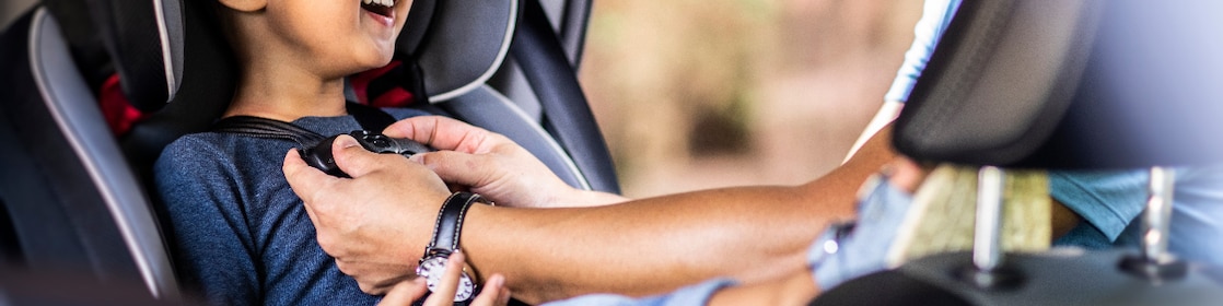 Father buckling son in car seat