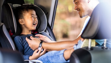 Father buckling son in car seat