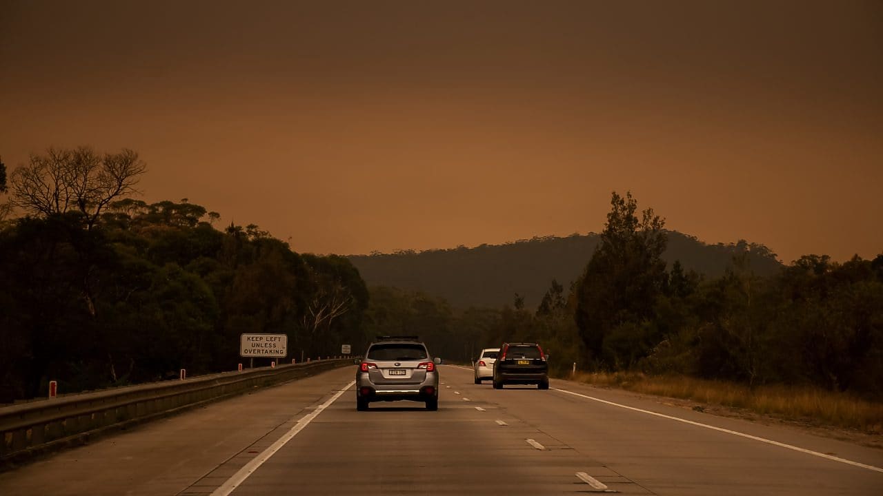Car driving on road with a smoke in the distance