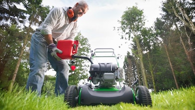 Man filling up his mower with a fuel container