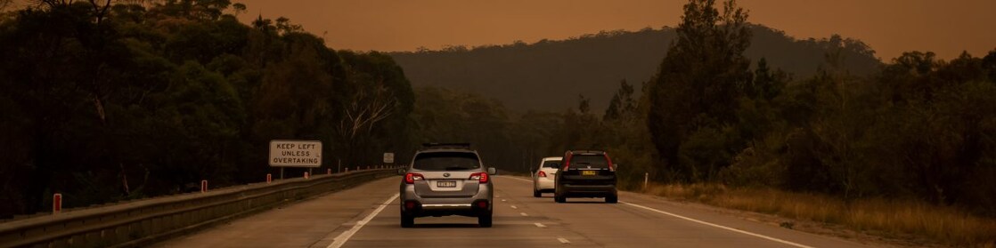 Car driving on road with a smoke in the distance
