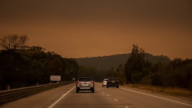 Car driving on road with a smoke in the distance