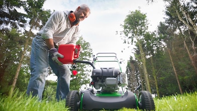 man filling up his mower with a fuel container