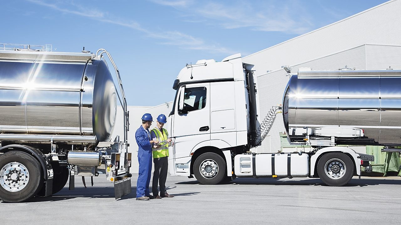 two technicians between two heavy oil trucks