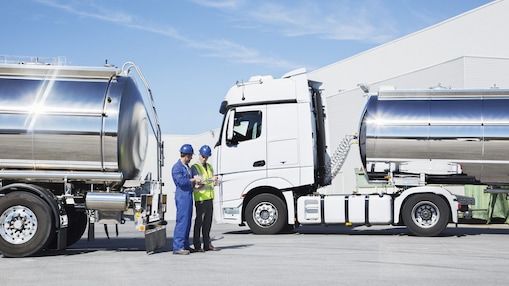 two technicians between two heavy oil trucks