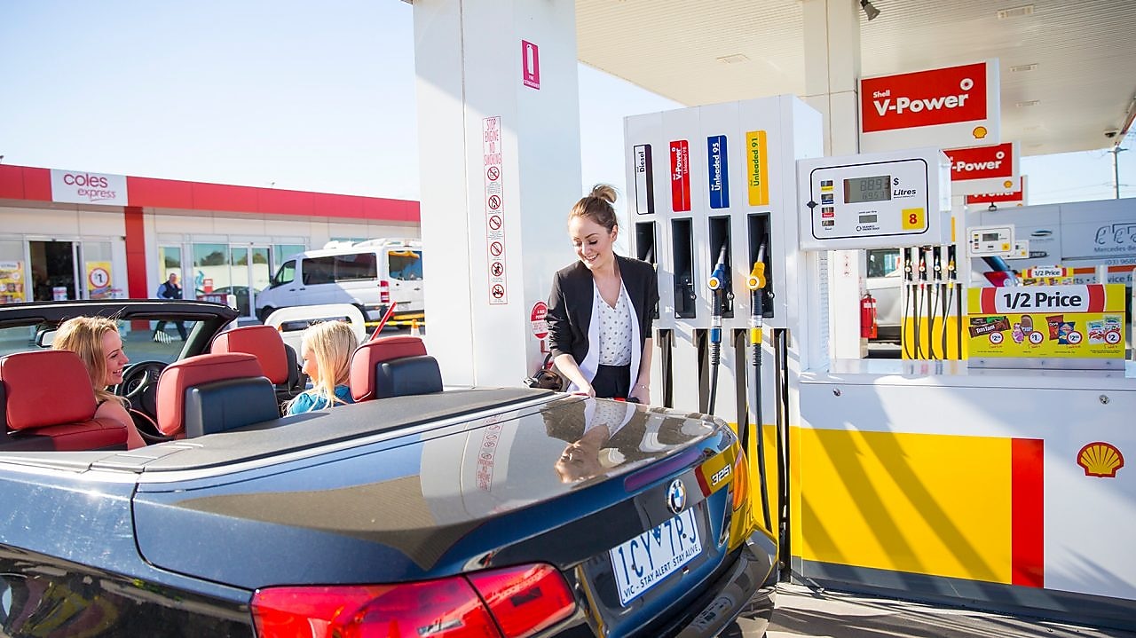 Woman refueling her car at a Shell Coles Express station
