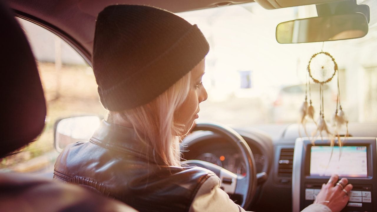 A young woman checks the instructions displayed on her car's built-in navigation screen