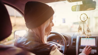 A young woman checks the instructions displayed on her car's built-in navigation screen