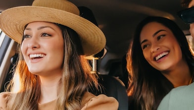 A group of three happy friends in a car on a road trip.