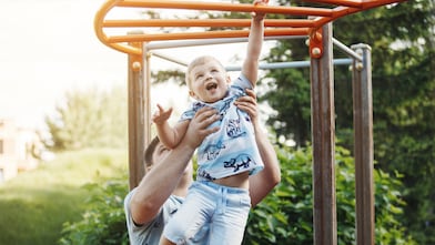 dad lifting and holding son on the monkey bars
