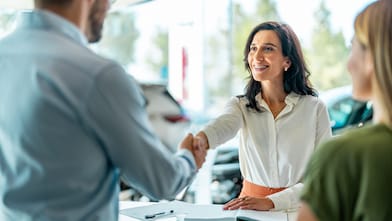 Business woman shaking hands with a male after a car loan agreement was signed.