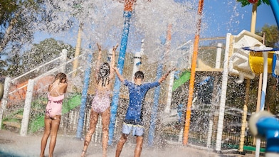 Three kids standing under water at a holiday park