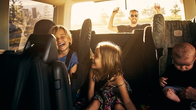 two kids and one baby sitting in the back of the car