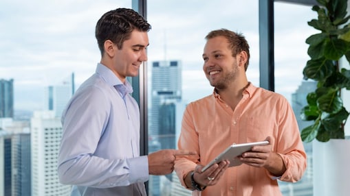 A couple of employees in an office discussing with a tablet